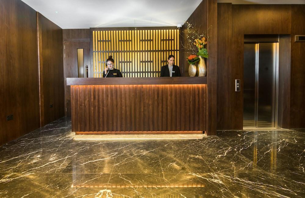 Montcalm Chilworth Townhouse, Paddington Hotel London Ngoại thất bức ảnh The photo shows a hotel reception area. At the front desk, two employees are standing behind a wooden counter. The wall behind the counter features a modern design with lines, and there are decorative elements, including a vase with flowers. The floo