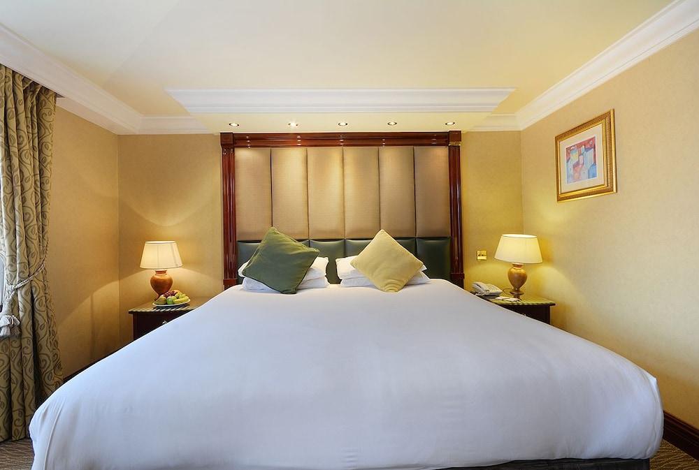 Montcalm Chilworth Townhouse, Paddington Hotel London Ngoại thất bức ảnh The photo shows a well-appointed hotel room featuring a large bed with a white blanket. The headboard is upholstered and includes decorative lighting above it. Two decorative pillows in shades of green and yellow are placed on the bed. On either side