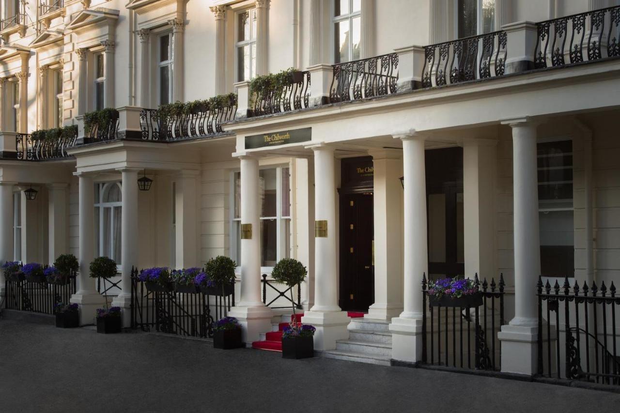 Montcalm Chilworth Townhouse, Paddington Hotel London Ngoại thất bức ảnh The photo shows an elegant building entrance with classic architectural features. It has several tall, white columns supporting a balcony adorned with ornamental railings. The entrance is flanked by decorative planters with flowers. A set of steps le