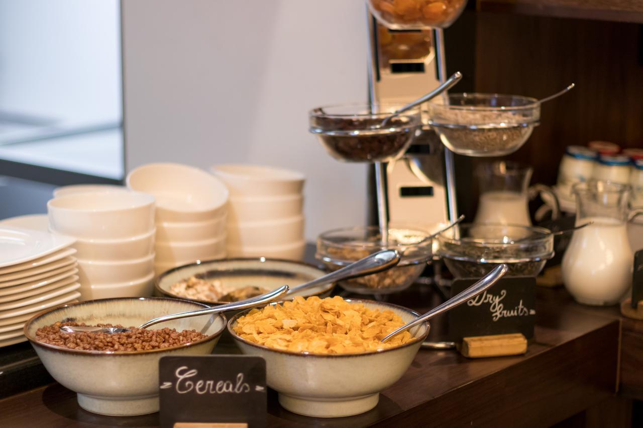 Montcalm Chilworth Townhouse, Paddington Hotel London Ngoại thất bức ảnh The photo shows a breakfast buffet setup featuring various cereals. There are multiple bowls containing different types of cereals, such as granola and possibly cornflakes. Each bowl has a spoon for serving. In the background, there are white plates 